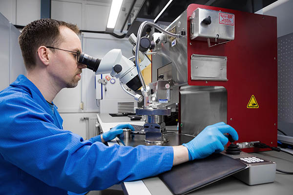 operator using a Royce pull-shear tester for testing strength and quality of wire bonds